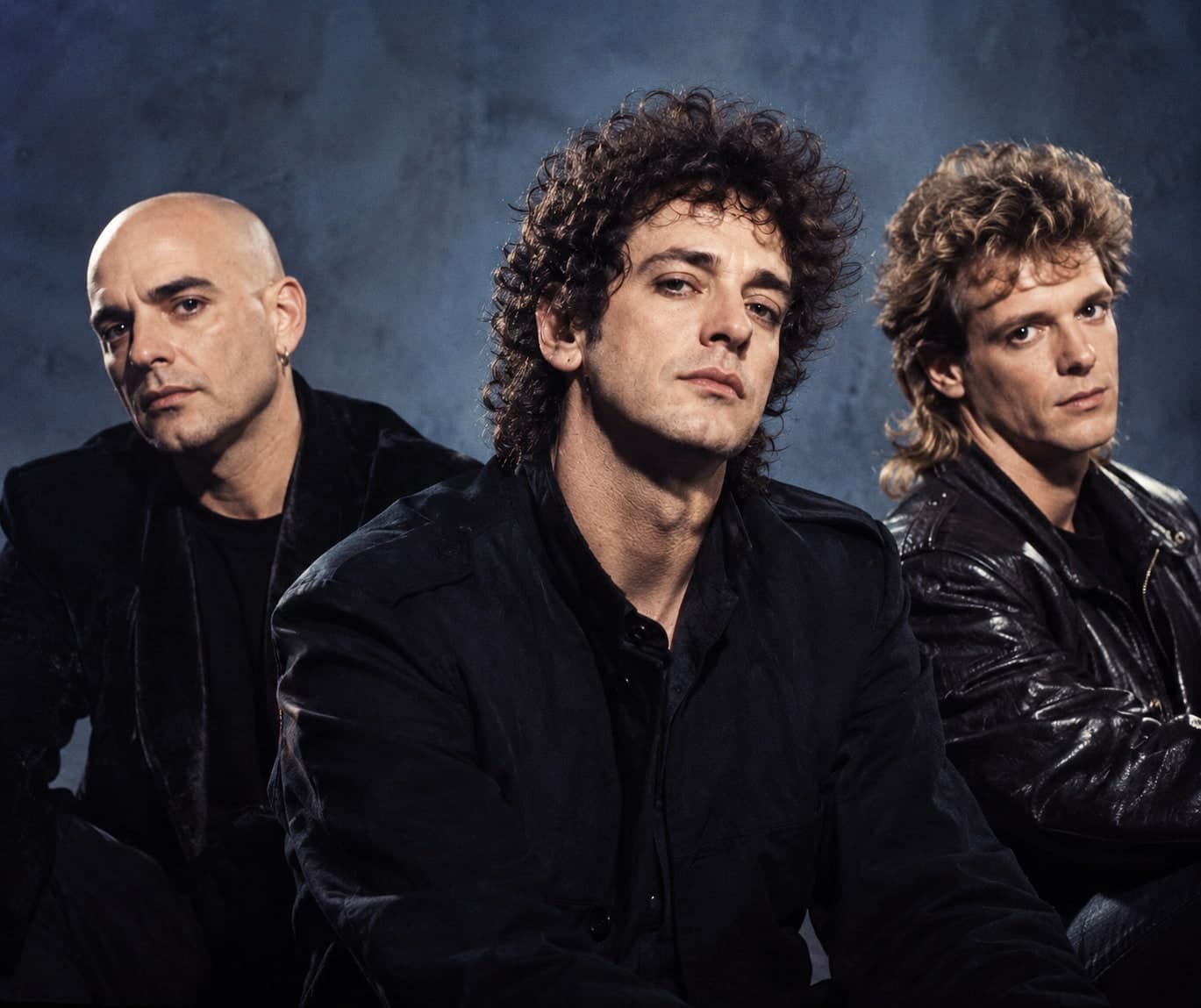 Os três integrantes do Soda Stereo em foto de estúdio, fundo azul
